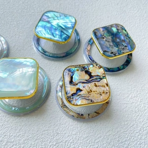 Macro view of square iridescent shell phone grips with luxury gold edges on white background