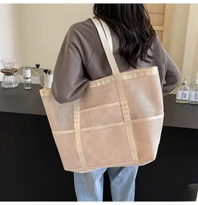 Detailed back view of a beige large mesh tote bag with wide straps on a model