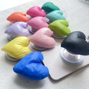 Close-up of colorful heart-shaped puffy fabric phone grips arranged on a white background