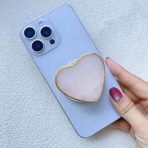 Détail du support de téléphone cœur en pierre naturelle rose avec dorure élégante sur mobile