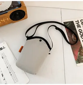 Close-up of light gray canvas phone bag with orange brand tag and snap button closure