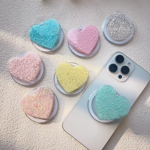 Glitter heart Magsafe phone grip sockets in pastel macaron colors on white textured background
