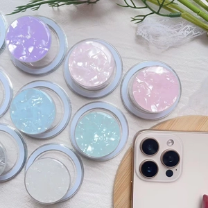 Detail view of round MagSafe phone grips featuring iridescent pastel shell paper patterns