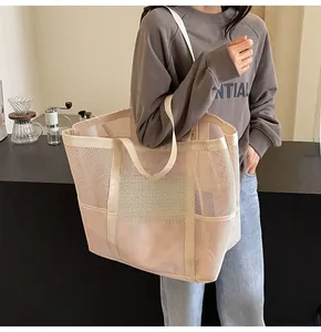 Detailed shoulder view of a beige mesh tote bag with reinforced straps and front pocket