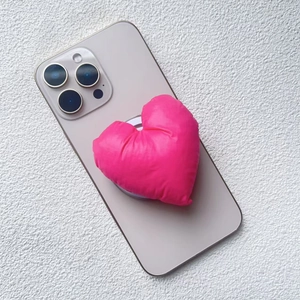 Close-up of a pink plush heart-shaped magnetic phone stand on a gold smartphone