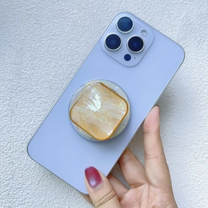Detail of a square shell pattern phone grip with gold frame on a blue smartphone