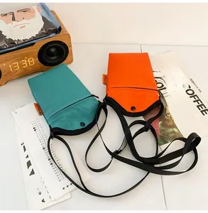 Detail view of blue and orange canvas mini crossbody bags with adjustable straps