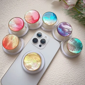 Colorful shell-textured phone grip set with gold metallic edges on white smartphone