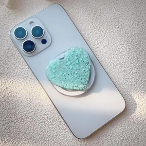 Macro view of mint green glitter heart phone grip with sequins on white smartphone