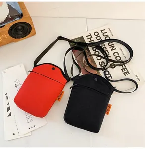 Close-up of red and black canvas crossbody bags with adjustable straps and side labels