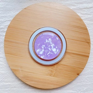 Detail of purple pearlescent shell pattern on circular magnetic phone socket over wood