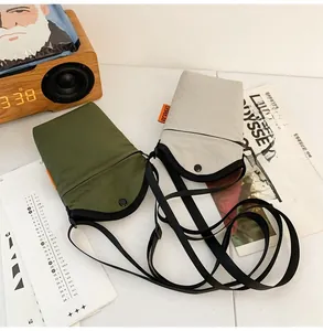 Detail of small nylon crossbody phone bags in olive and grey with brand labels
