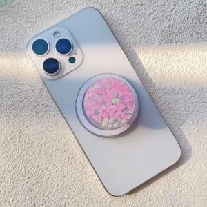 Detail of pink heart glitter and sequins inside the magnetic phone grip on a white device