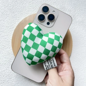 Close-up of green and white checkered heart fabric phone stand with a soft plush texture