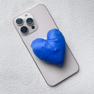 Blue heart-shaped puffy fabric magnetic phone stand on a grey smartphone back