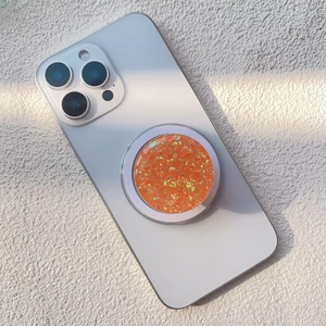 Macro shot of bright orange glitter phone grip attached to a white iPhone back