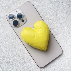 Detail view of heart-shaped yellow padded cotton phone stand with a 3D puffy fabric texture