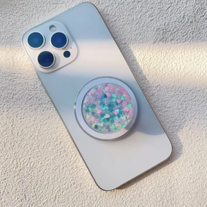 Detail of magnetic glitter phone grip with heart-shaped sequins on blue smartphone