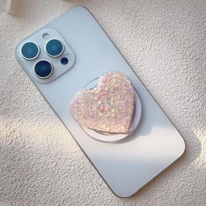 Detail view of heart-shaped glitter phone socket with pink sequins on a white smartphone