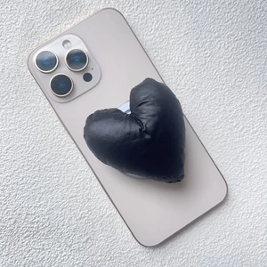 Detail of a black quilted heart phone grip with soft padded texture on a smartphone
