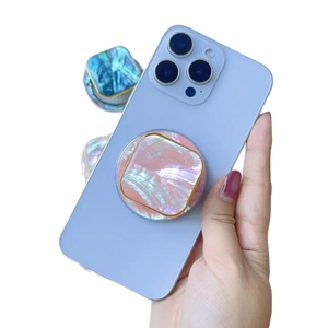 Pink shell texture phone socket with gold trim on a blue smartphone held by hand
