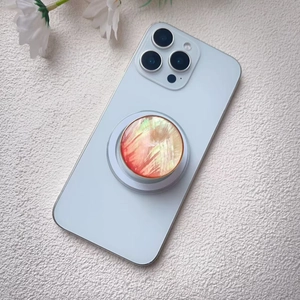 Detail of artistic shell-textured phone grip with gold trim on a blue smartphone