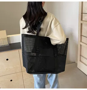 Detail of a large black mesh tote bag with reinforced straps for beach or daily use