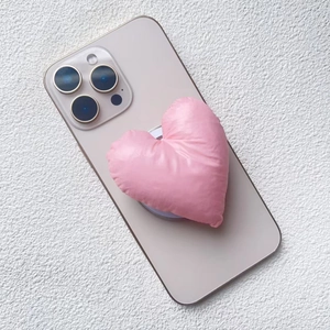 Close-up of pink heart-shaped puffy fabric phone stand with a soft satin finish texture