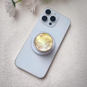 Macro shot of shell texture phone grip with gold trim and retractable stand on white phone