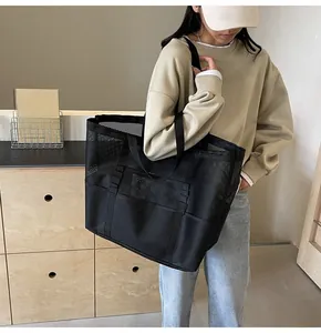 Detail of black mesh tote bag showing large capacity structure and functional outer pocket
