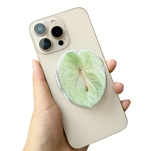 Detail showing green acrylic leaf phone socket with leaf vein texture on a beige smartphone