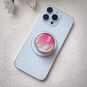 Detail showing pink shell texture phone grip with golden edge on white smartphone