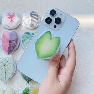 Detail of green heart-shaped leaf acrylic magnetic phone grip on a white surface