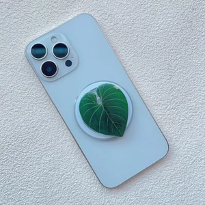 Close-up of green heart-shaped leaf phone grip with detailed texture on white smartphone