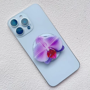 Detail view of a purple orchid phone grip attached to the back of a blue smartphone