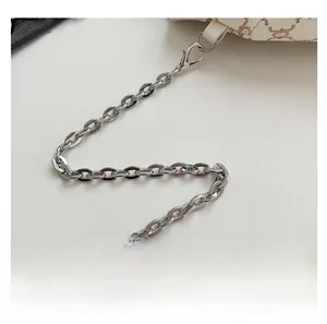 Detailed close-up of silver chain strap on beige monogram patterned crossbody bag