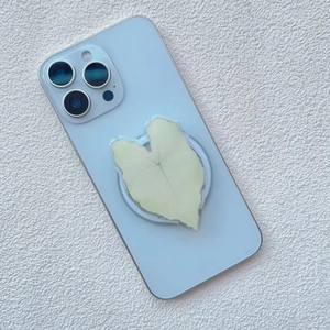 Detail of leaf-shaped acrylic phone grip with yellow veins on a blue smartphone