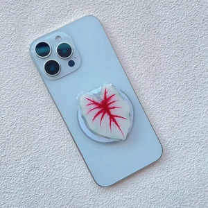 Close-up of a green leaf shaped magnetic phone grip attached to a light blue smartphone