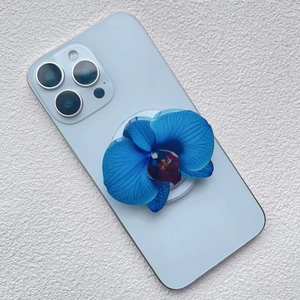 Close-up of blue orchid acrylic magnetic phone grip on a light blue smartphone