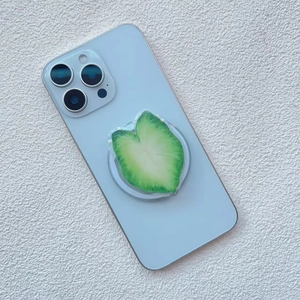 Macro detail of leaf-shaped acrylic phone grip mounted on light blue smartphone