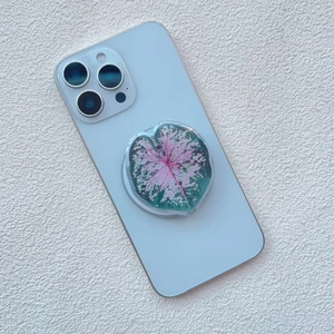 Macro view of a heart-shaped caladium leaf phone grip on a light blue smartphone