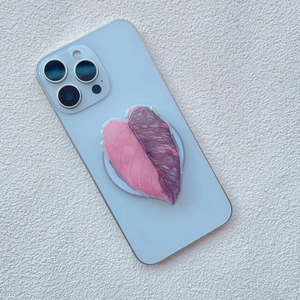Macro detail of leaf-shaped acrylic phone grip with pink gradient leaf texture on blue phone