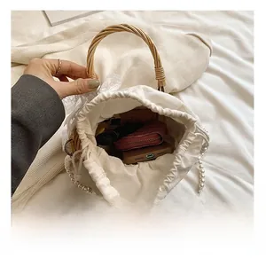 Detail view of woven straw bag interior with drawstring lining and pearl strap
