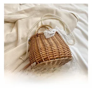 Detail of straw woven bag with lace bow, wooden handle and pearl crossbody chain strap