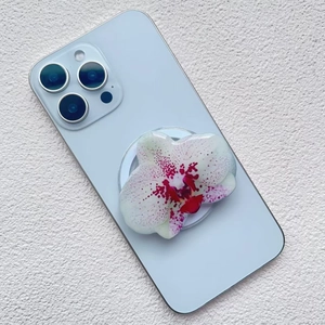 Detail of orchid-shaped acrylic phone grip with purple spots on a blue smartphone