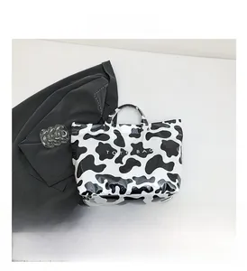 Détail du sac cabas brillant à motif vache montrant la texture du cuir poli