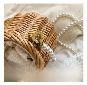 Detail showing woven straw texture with white pearl strap and bronze metal clasp