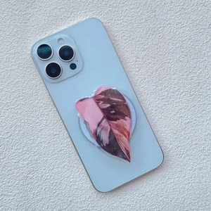 Close-up of pink variegated leaf phone socket mount on a light blue smartphone case