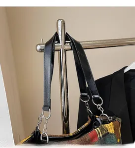 Detail of plaid tote bag featuring checkered tweed texture and chain leather strap