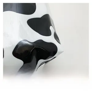 Gros plan du sac cabas à imprimé vache brillant montrant la texture du tissu PVC